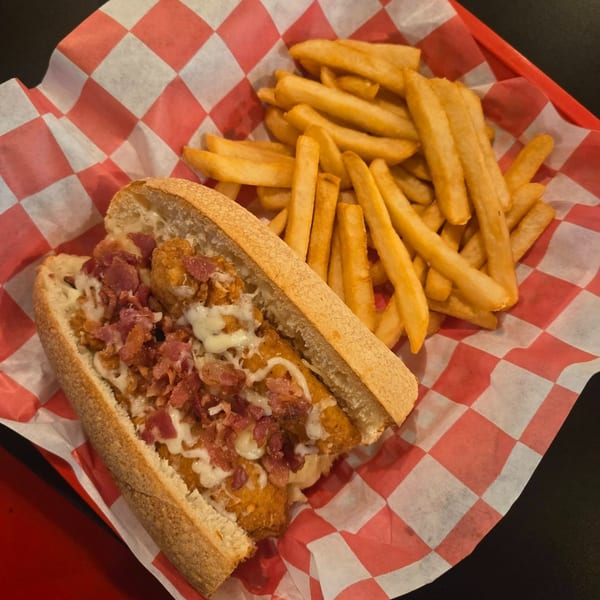 A chicken bacon ranch sub with fries in a red and white checkered basket.